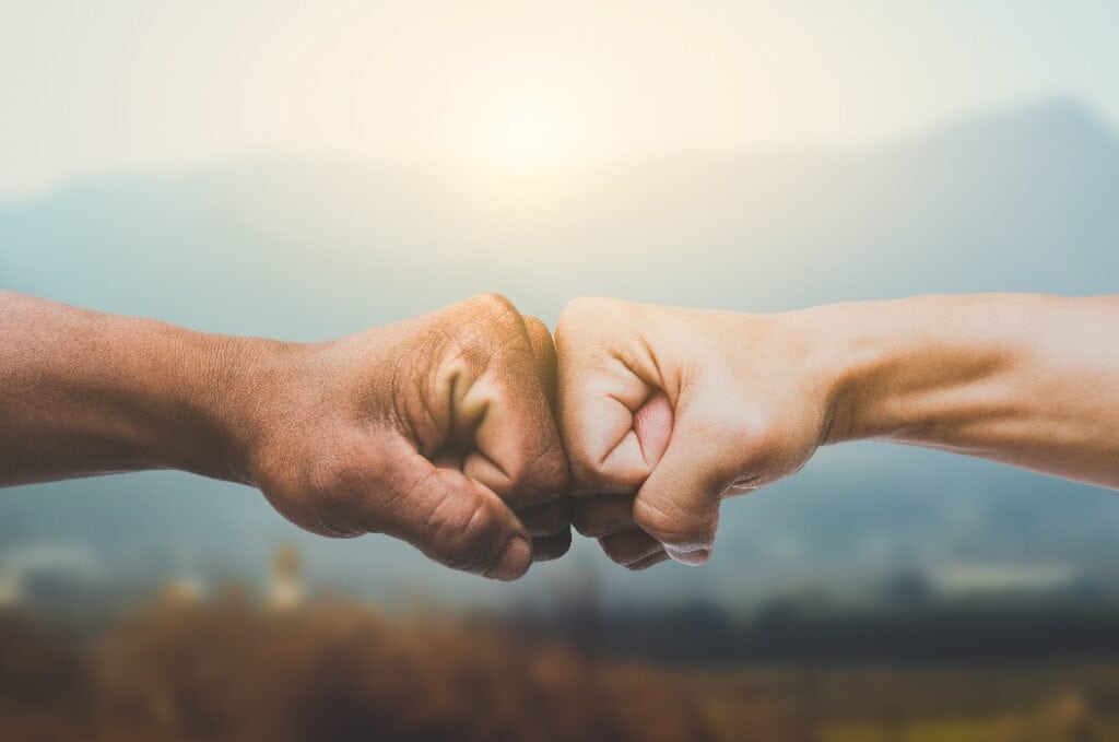 Man giving fist bump in sun rising nature background. power of teamwork concept. vintage tone